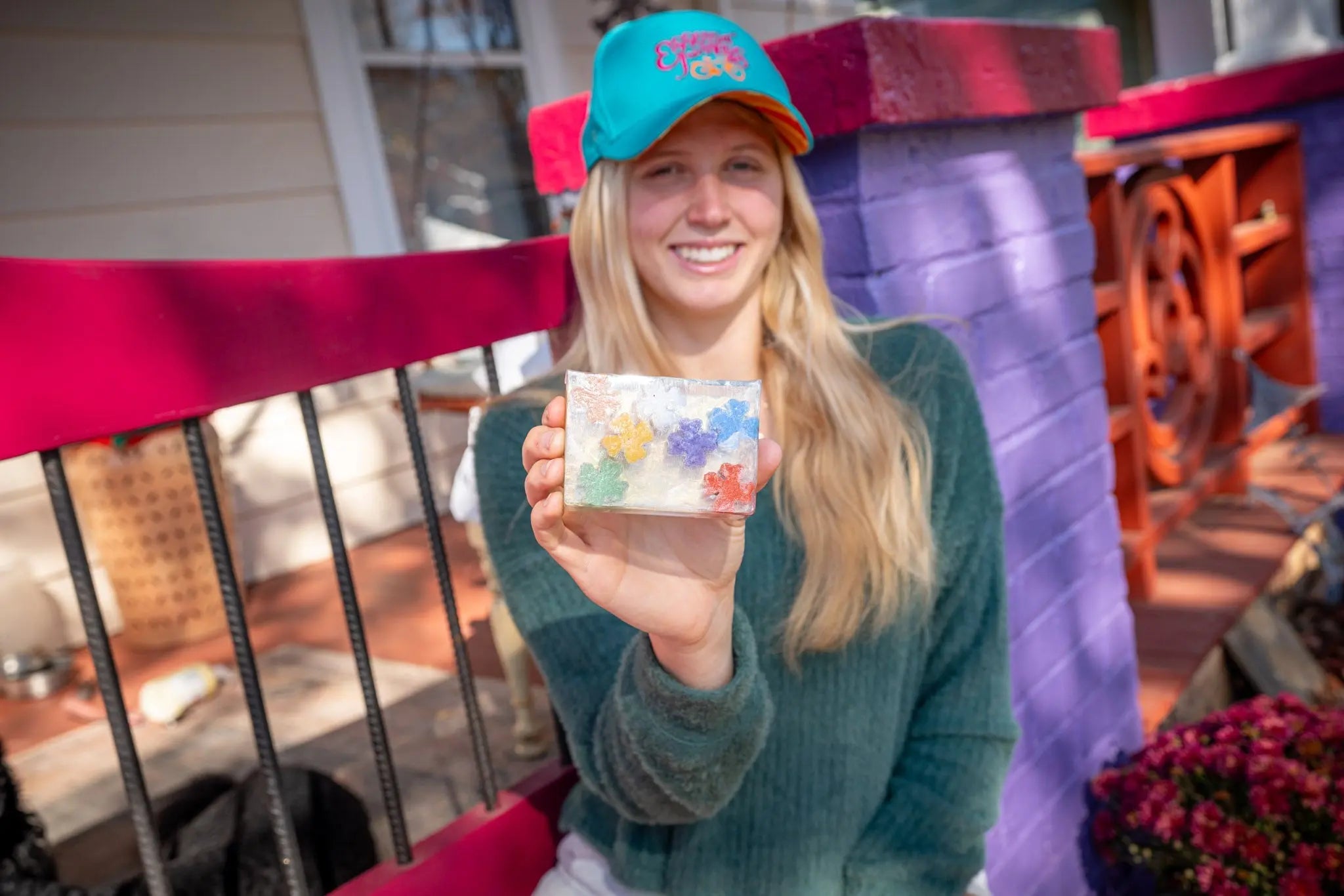Woman holding a slice of clear soap with colorful flower embeds.