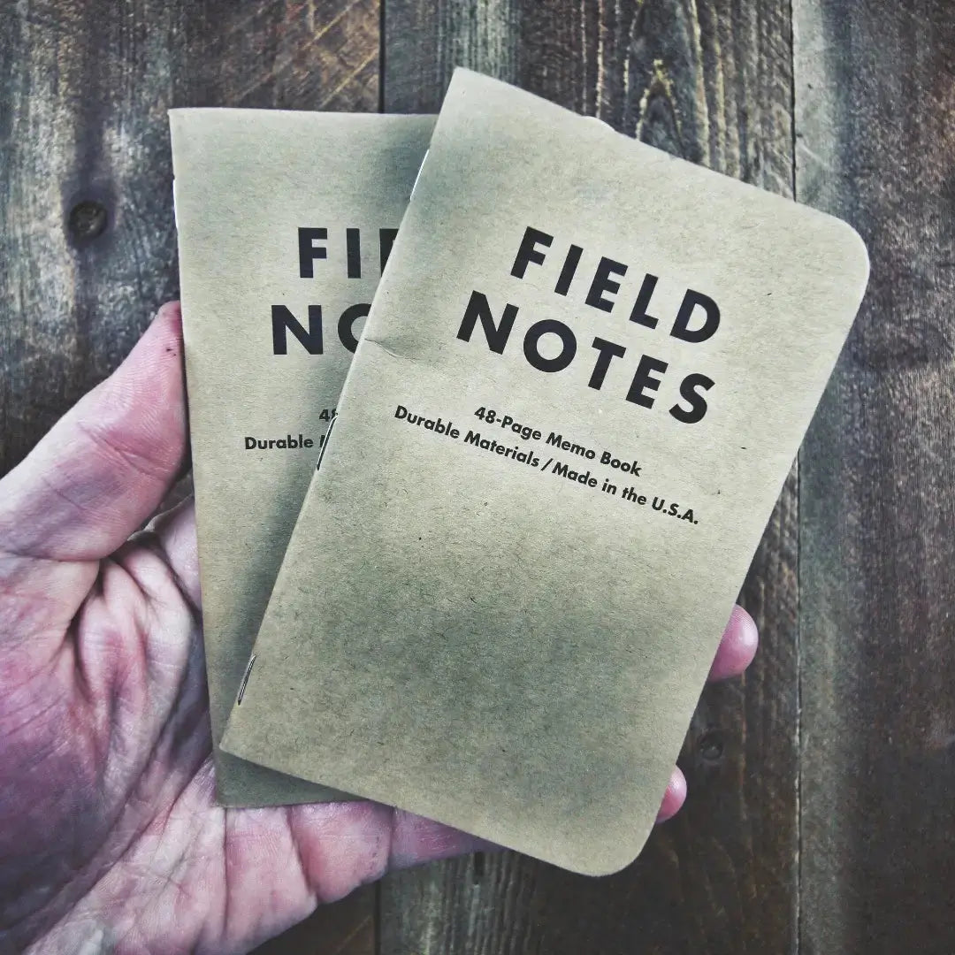 Two brown Field Notes memo books held in a hand
