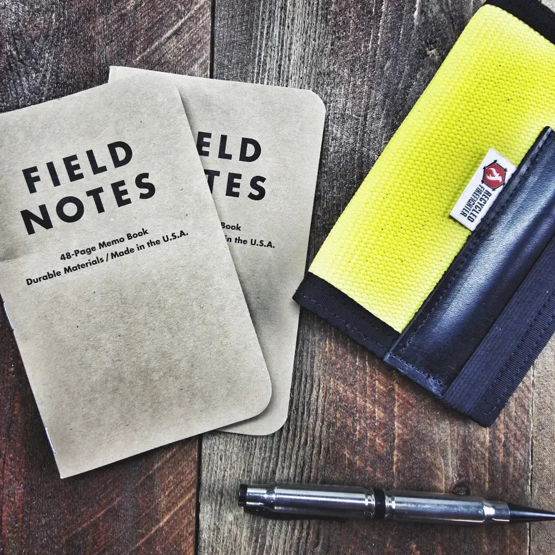 Field Notes notebooks and a pen on a wooden surface, with a yellow canvas item.