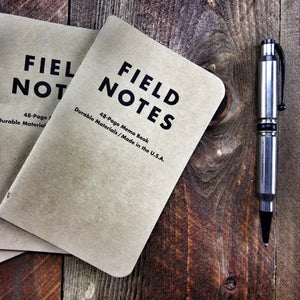 Field Notes notebook with kraft cover and graph paper next to a silver pen.