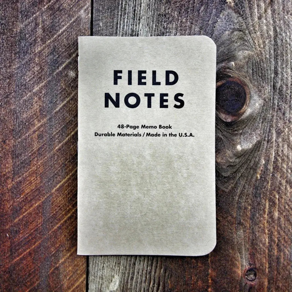 Field Notes notebook with "FIELD NOTES" logo and graph paper details on wooden background.