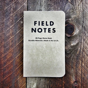 Field Notes notebook with "FIELD NOTES" logo and graph paper details on wooden background.