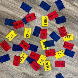 Assortment of colorful firehose patches with visible text like PSI, dates, and service markings on a wooden background.