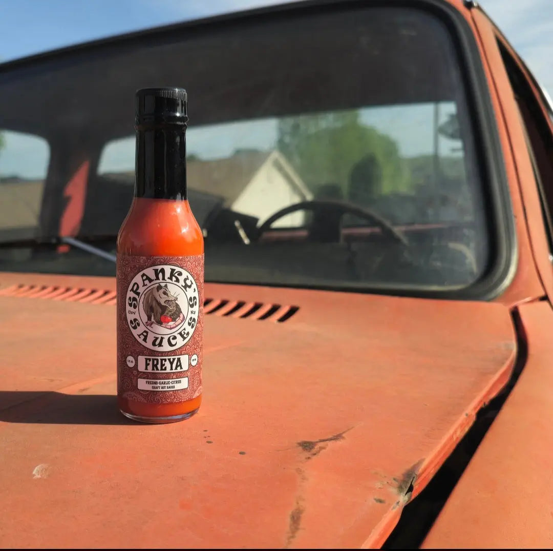 Spanky's Sauces Freya hot sauce bottle on the hood of an orange truck.