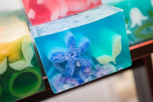 GARDEN BLOSSOMS SOAP SLICE with blue flower and purple pieces in clear blue soap