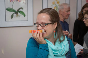 Woman smiling and smelling a slice of grapefruit goat milk soap.