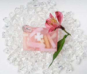 Pink grapefruit splash soap slice with white flower shapes on ice with a pink flower.