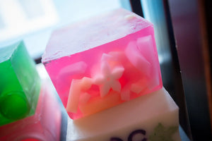 Green and pink layered soap slices with visible fruit pieces and flower shapes