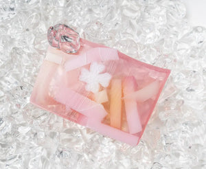 Pink grapefruit splash soap slice with white flower design and colored bar inclusions.
