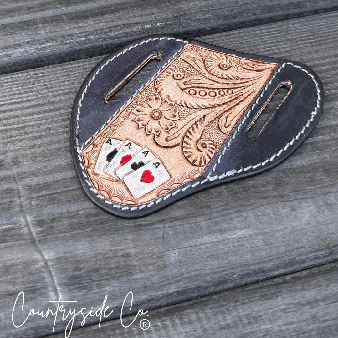 Tooled leather knife sheath with a playing cards and floral design.