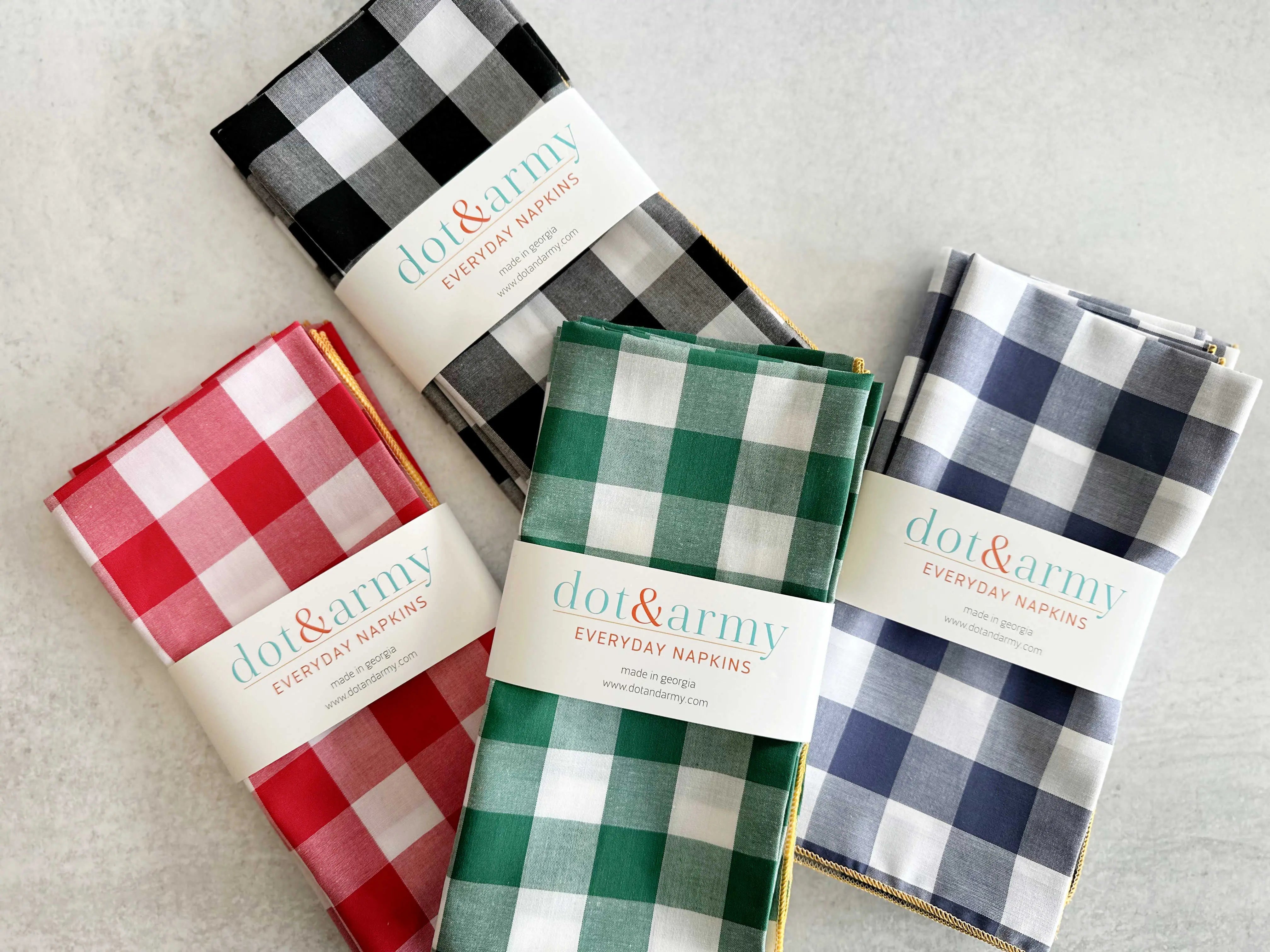 Four gingham cloth napkins in red, green, blue, and black with white checks.