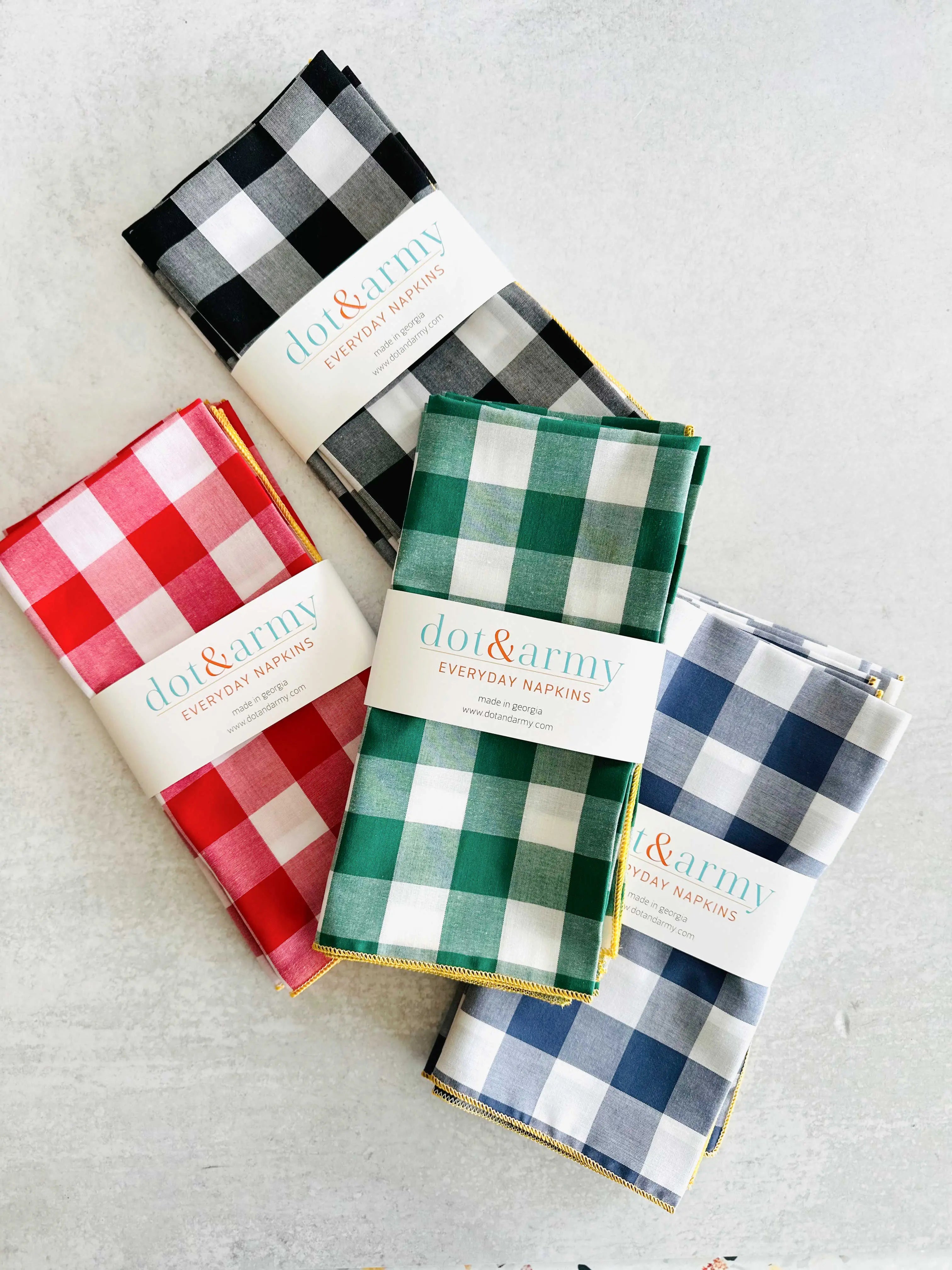 Set of four gingham check cloth napkins in red, black, green, and blue.