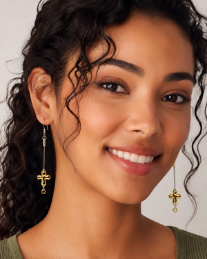 Woman wearing gold cross earrings with a neutral background