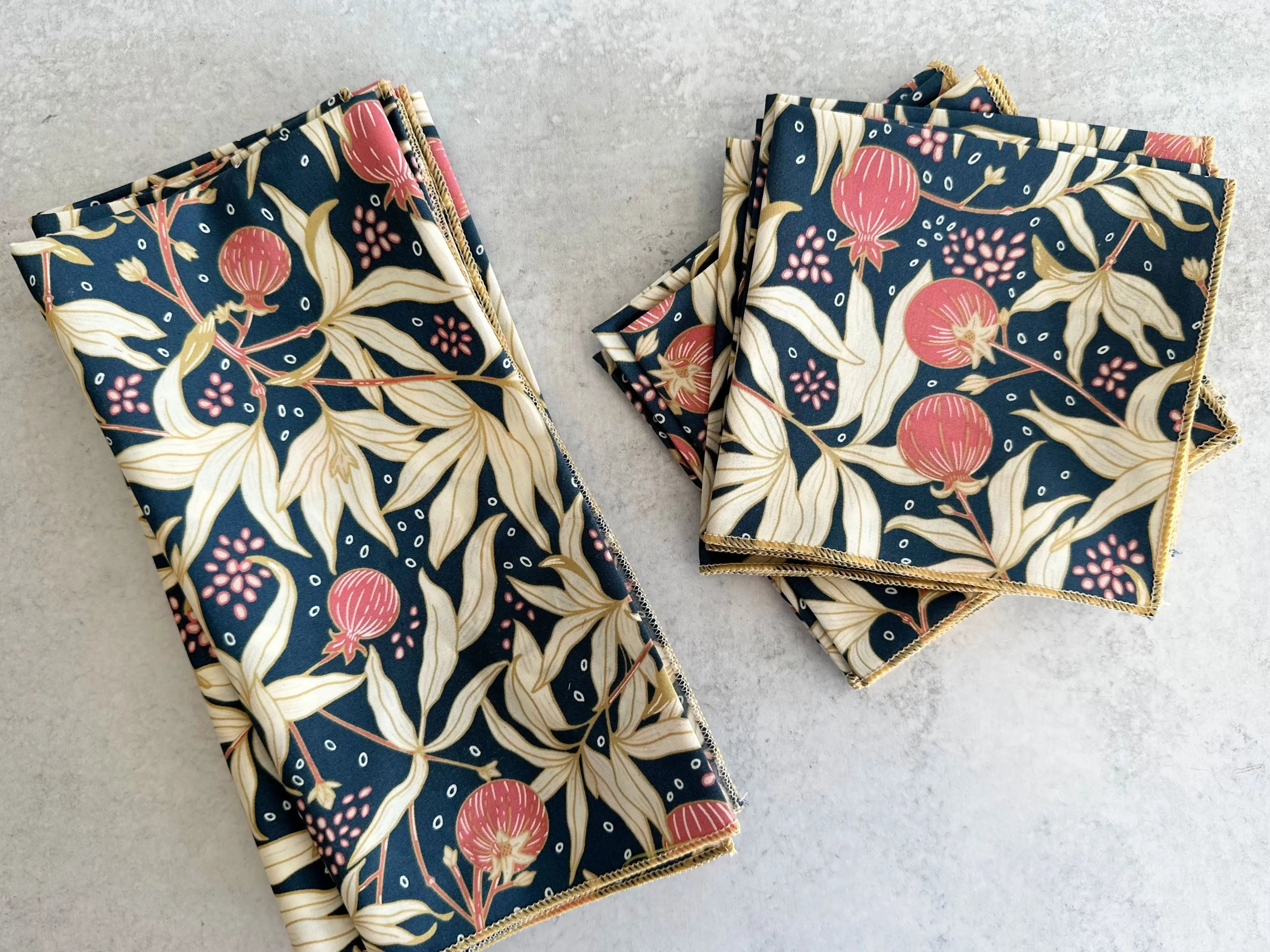 Dark blue cloth napkins with gold trim featuring pomegranate and leaf pattern.
