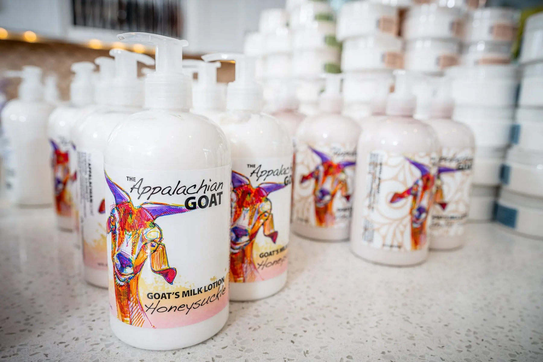 The Appalachian Goat Honeysuckle Goat's Milk Lotion bottles with colorful goat illustrations