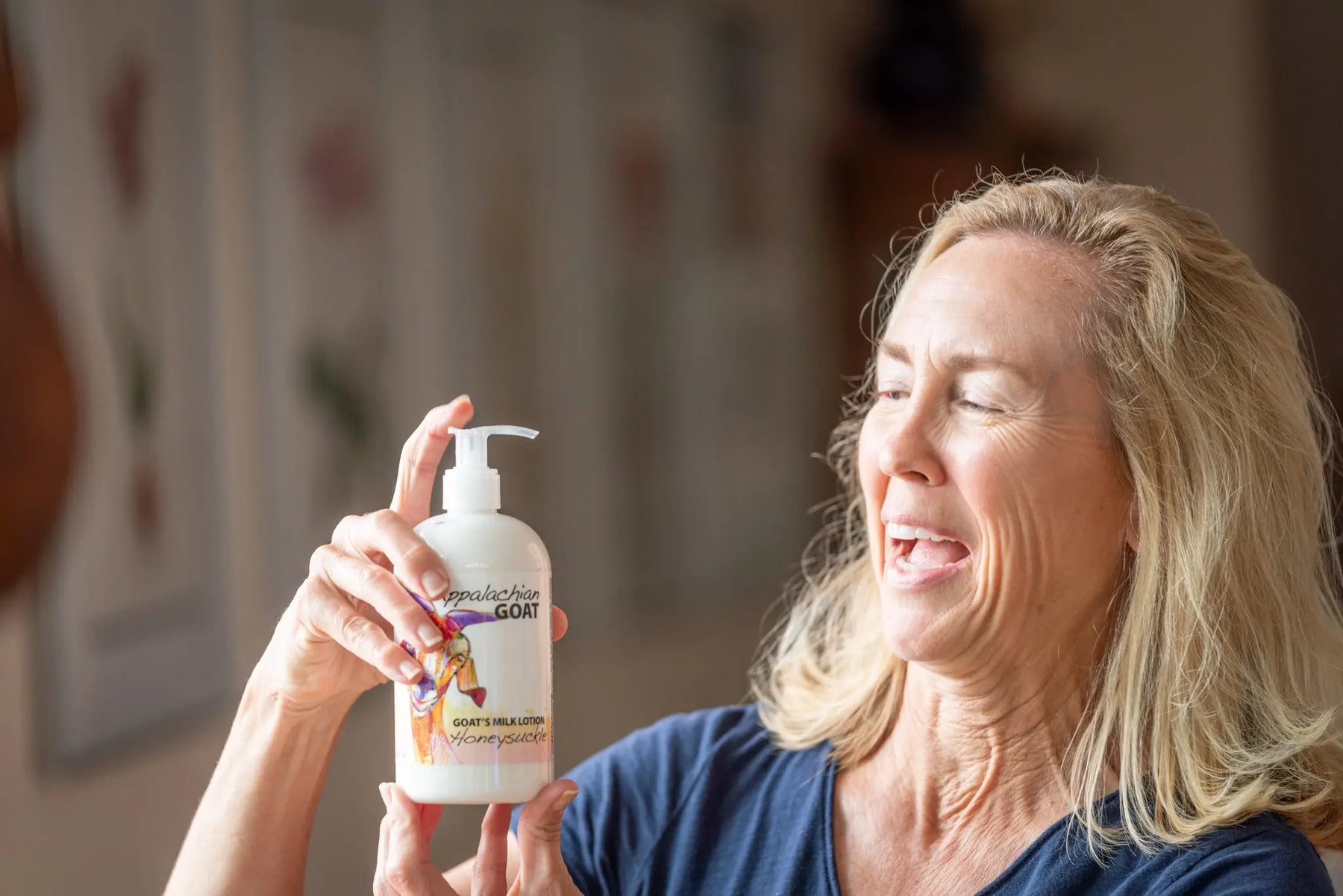 Woman holding Appalachian Goat Honeysuckle Goat's Milk Lotion bottle with a white pump.