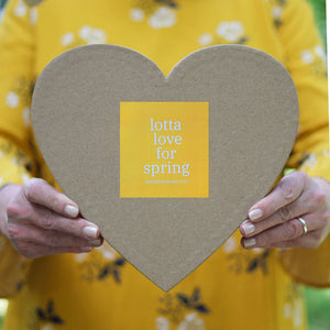 Heart-shaped box with a yellow sticker featuring white text.