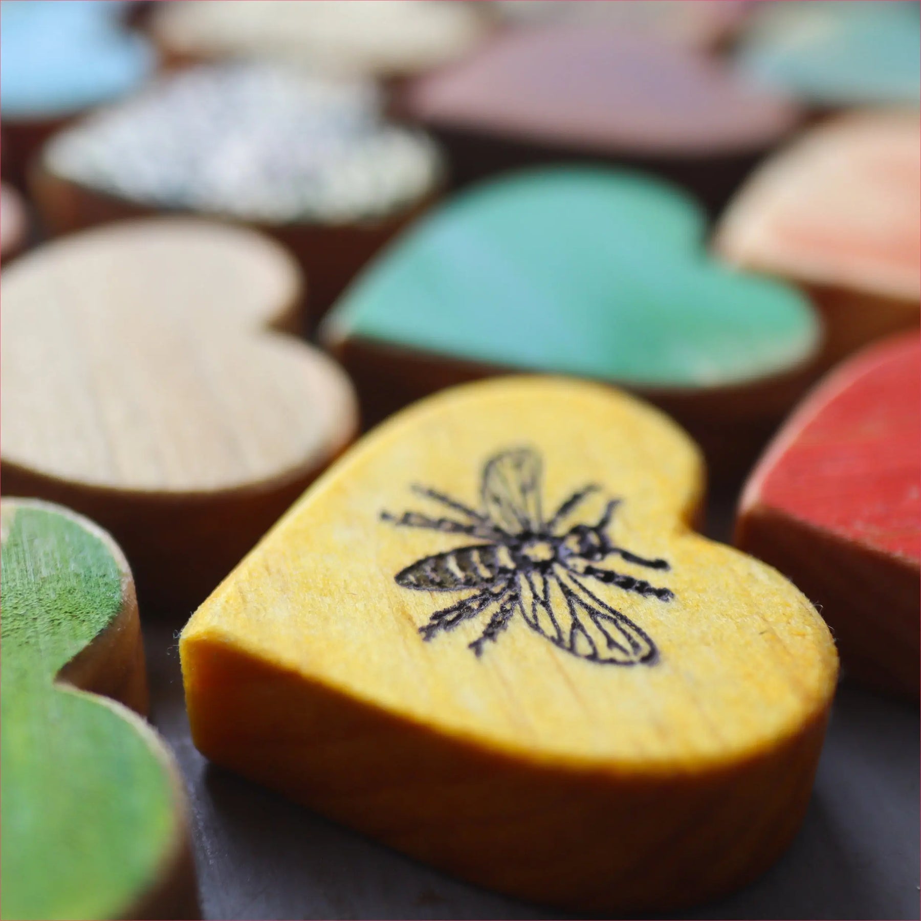 Assorted heart-shaped wooden pieces with painted colors and engraved designs.