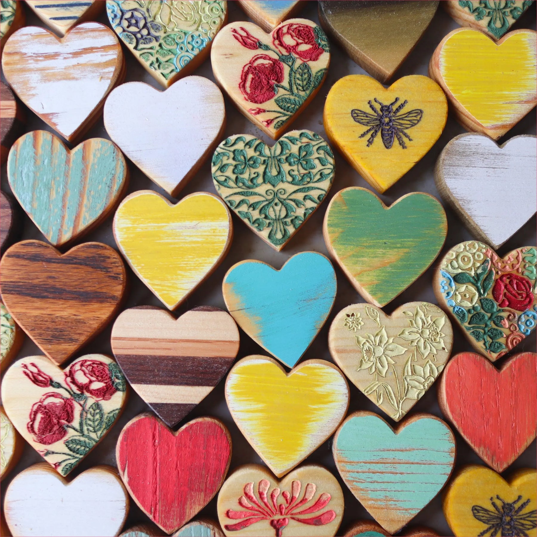 Assortment of colorful wooden heart decorations with various patterns and textures.