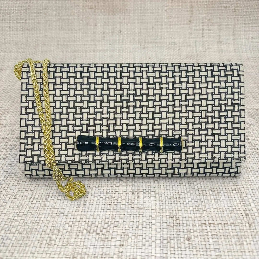 Black and white woven pattern clutch with gold chain and bamboo-style closure.