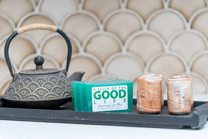 Japanese Matcha soap slices with a small cast iron teapot and ceramic cups on a dark tray.