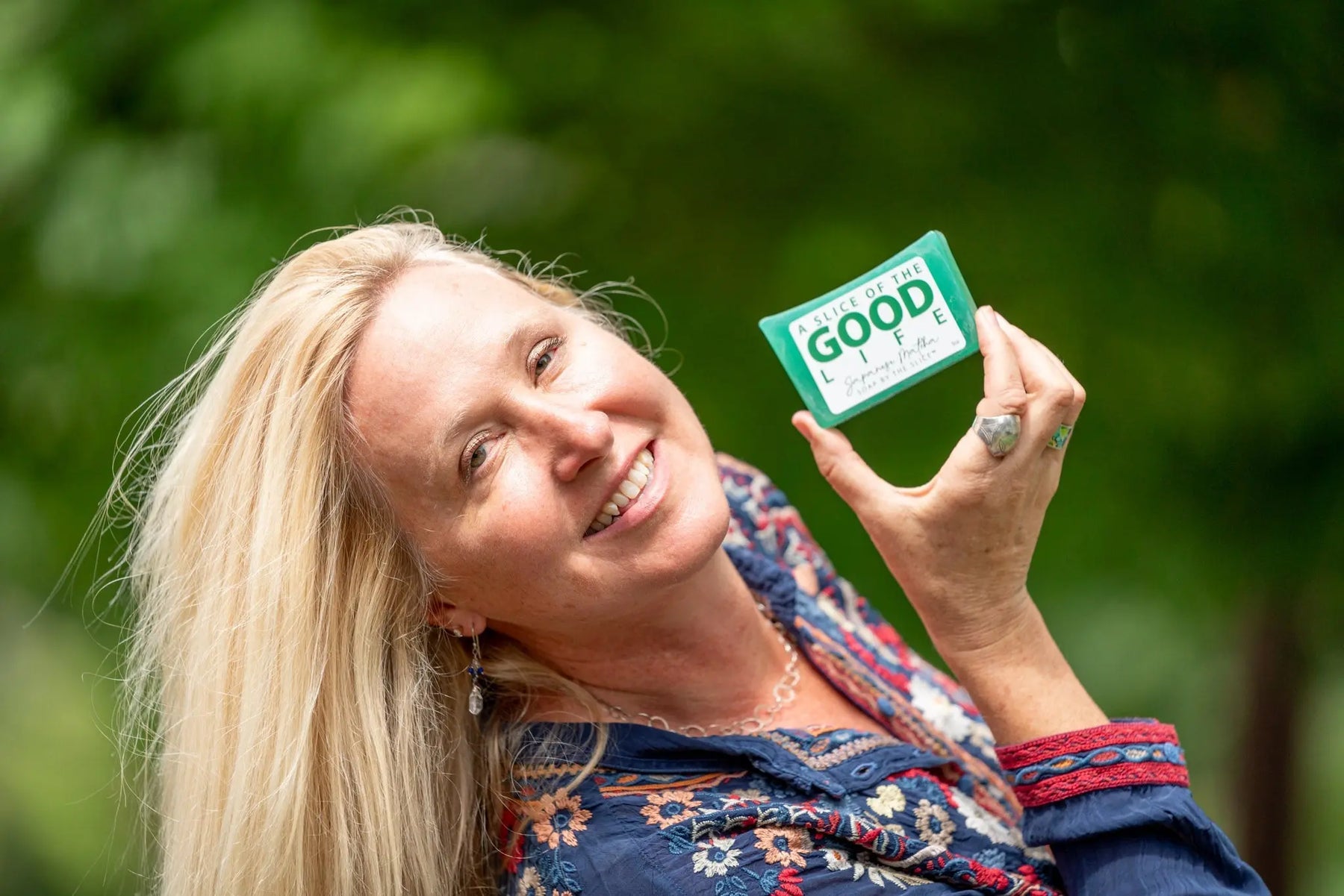 Woman smiling and holding a green bar of Japanese Matcha soap.