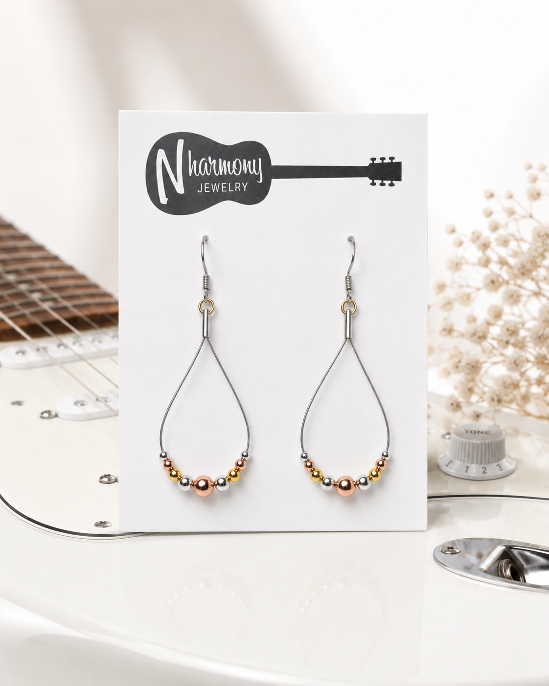 Pair of beaded earrings on a 'N Harmony Jewelry' card with a guitar and decorative elements in the background.