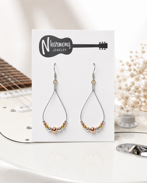 Pair of beaded earrings on a 'N Harmony Jewelry' card with a guitar and decorative elements in the background.