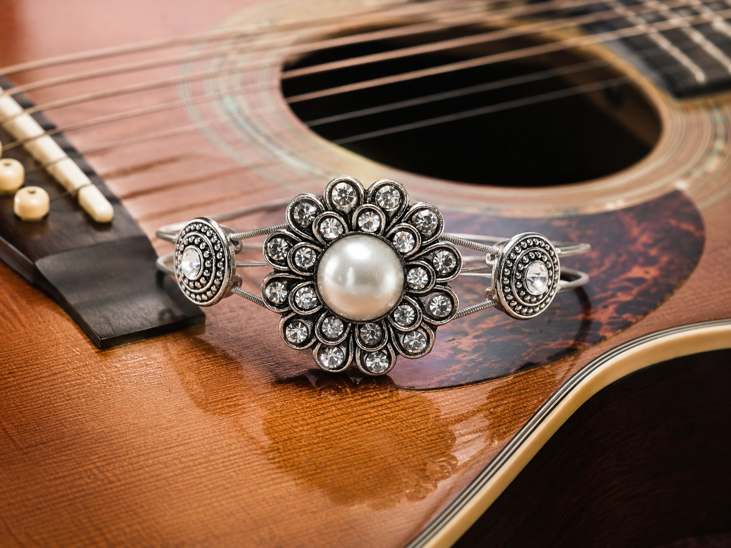 Silver rhinestone and pearl guitar string bracelet on acoustic guitar