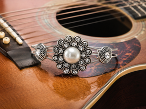 Silver rhinestone and pearl guitar string bracelet on acoustic guitar