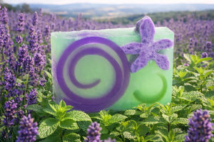 Green and purple lavender mint soap bar with floral accents in a lavender field.