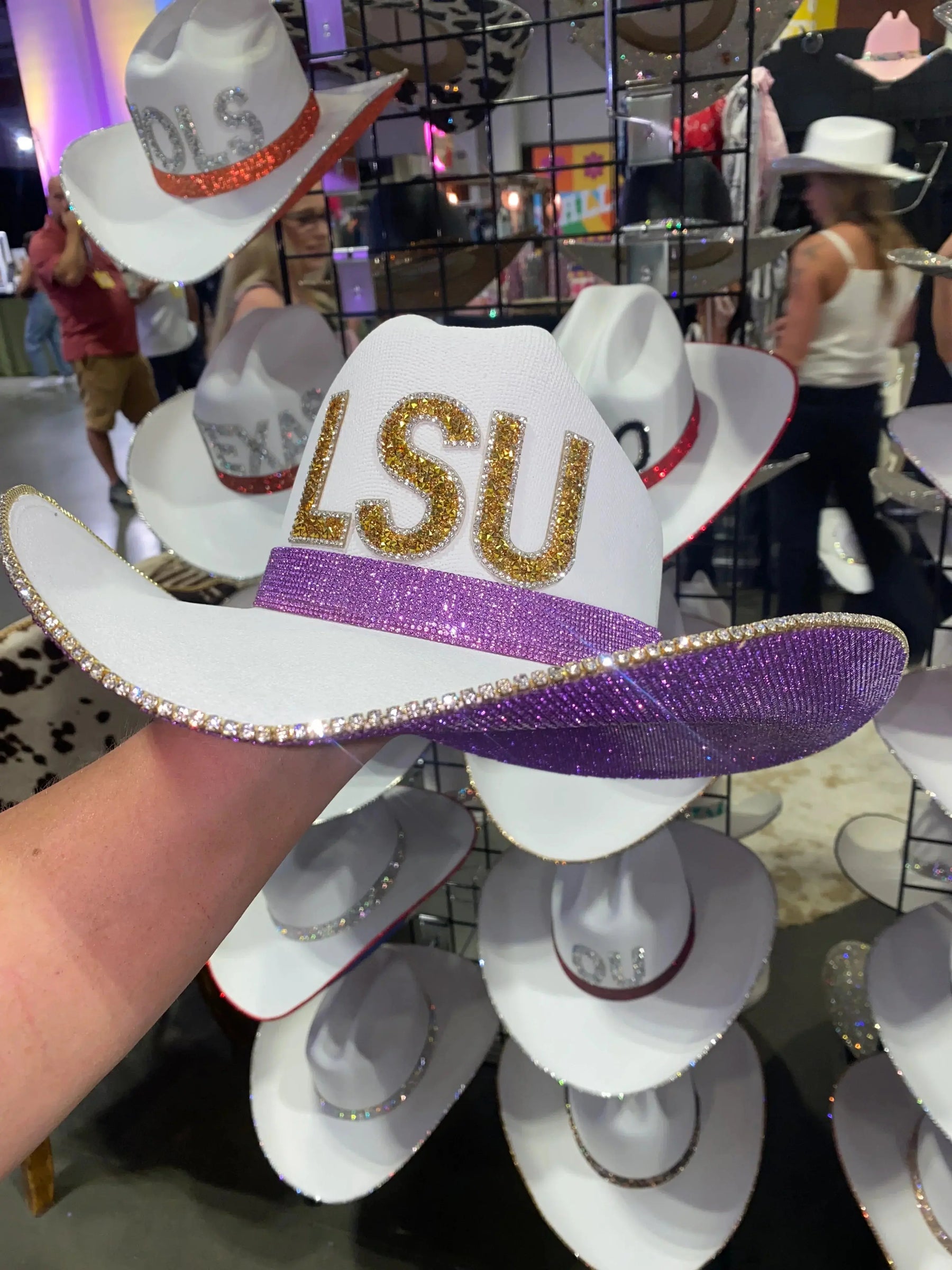 White cowgirl hat with gold LSU letters and purple rhinestone band.
