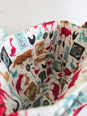 Canvas tote bag interior with farm animal print (cows, chickens, geese) and "Farm Sweet Farm" sign, revealing its open shopper style.