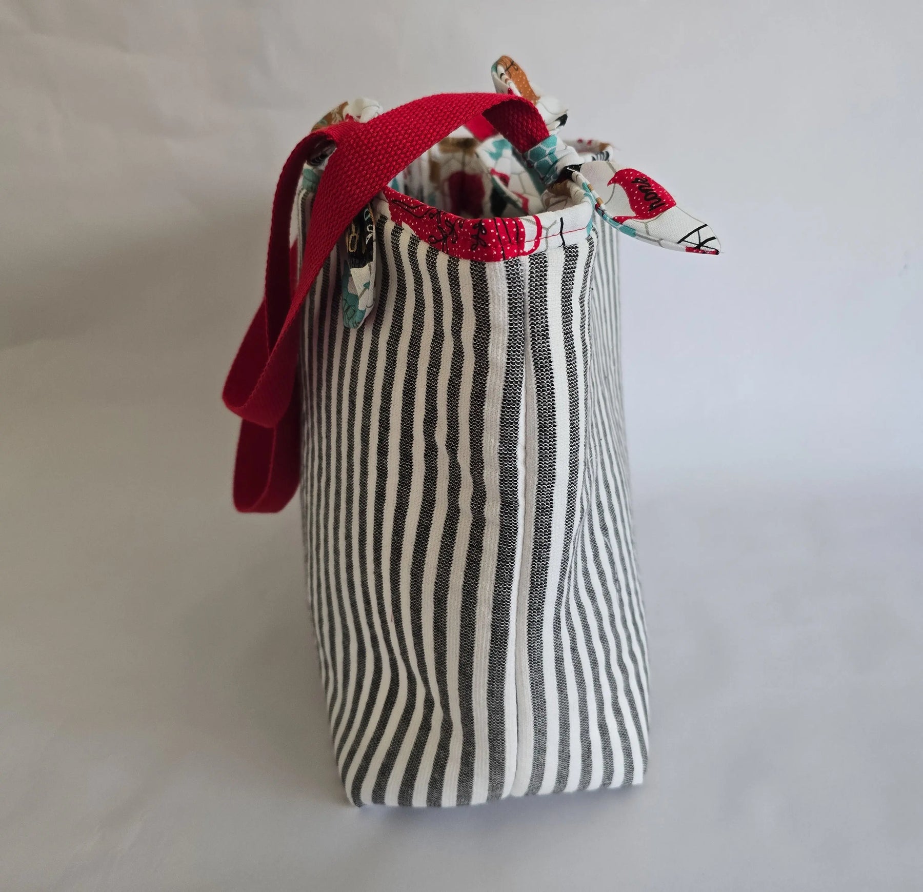 Black and white striped canvas tote bag with red shoulder straps. Reusable shoulder bag.