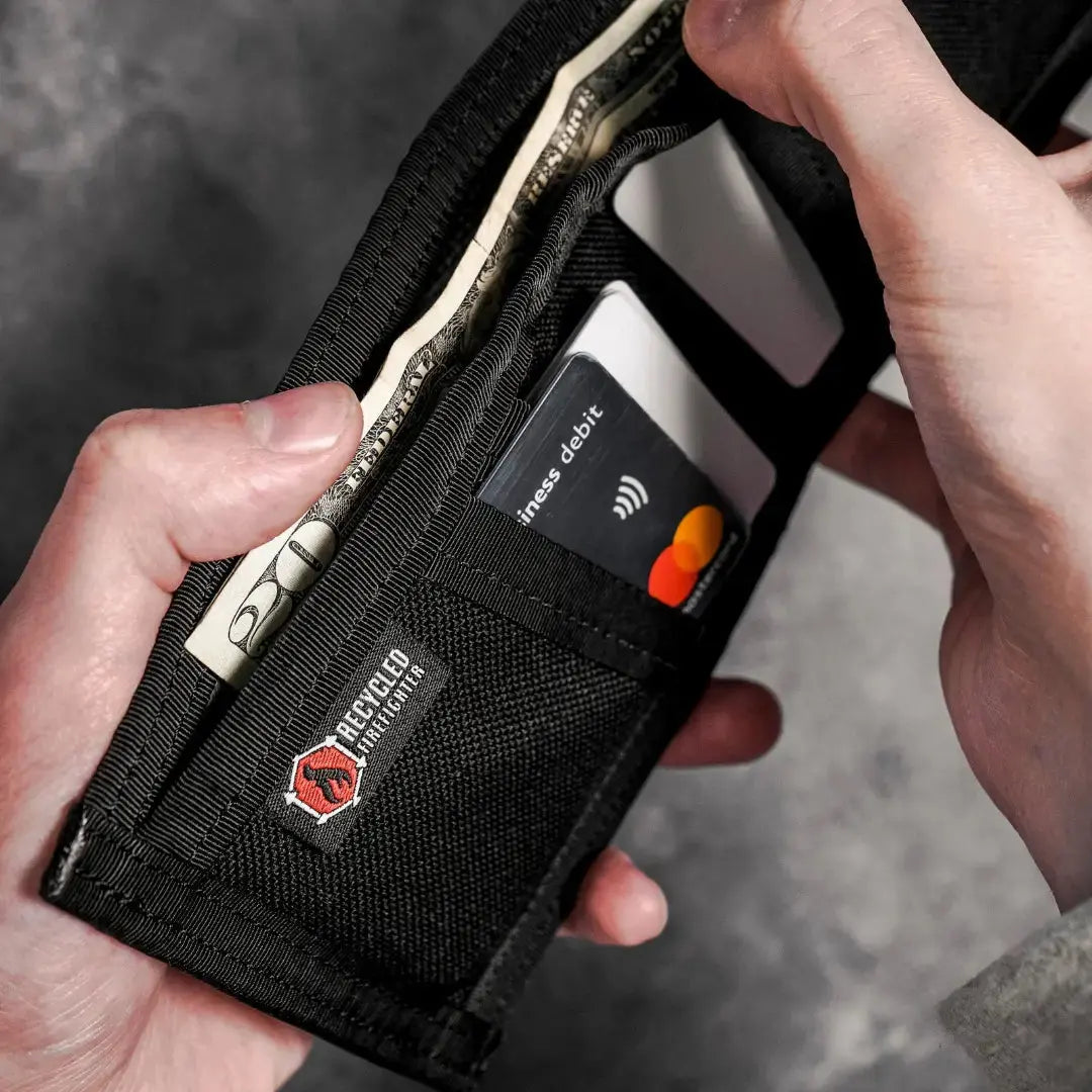 Black wallet holding US dollar bills and a debit card.