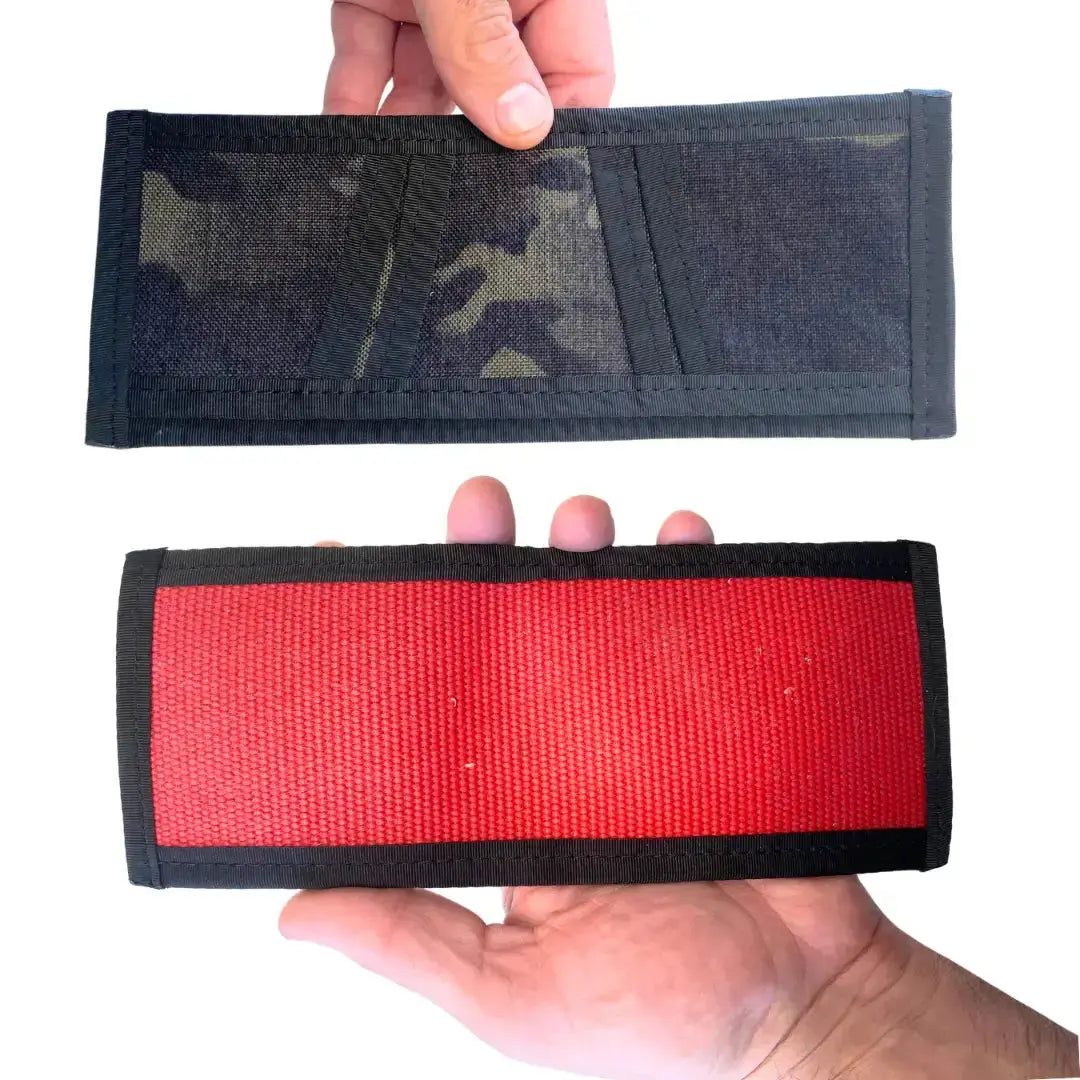 Two wallets held in hands, one with camouflage pattern, one red.