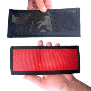 Two wallets held in hands, one with camouflage pattern, one red.