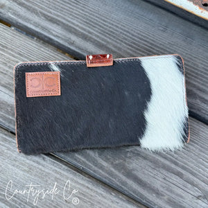 Black and white cowhide Countryside Co. wallet with a leather logo patch.