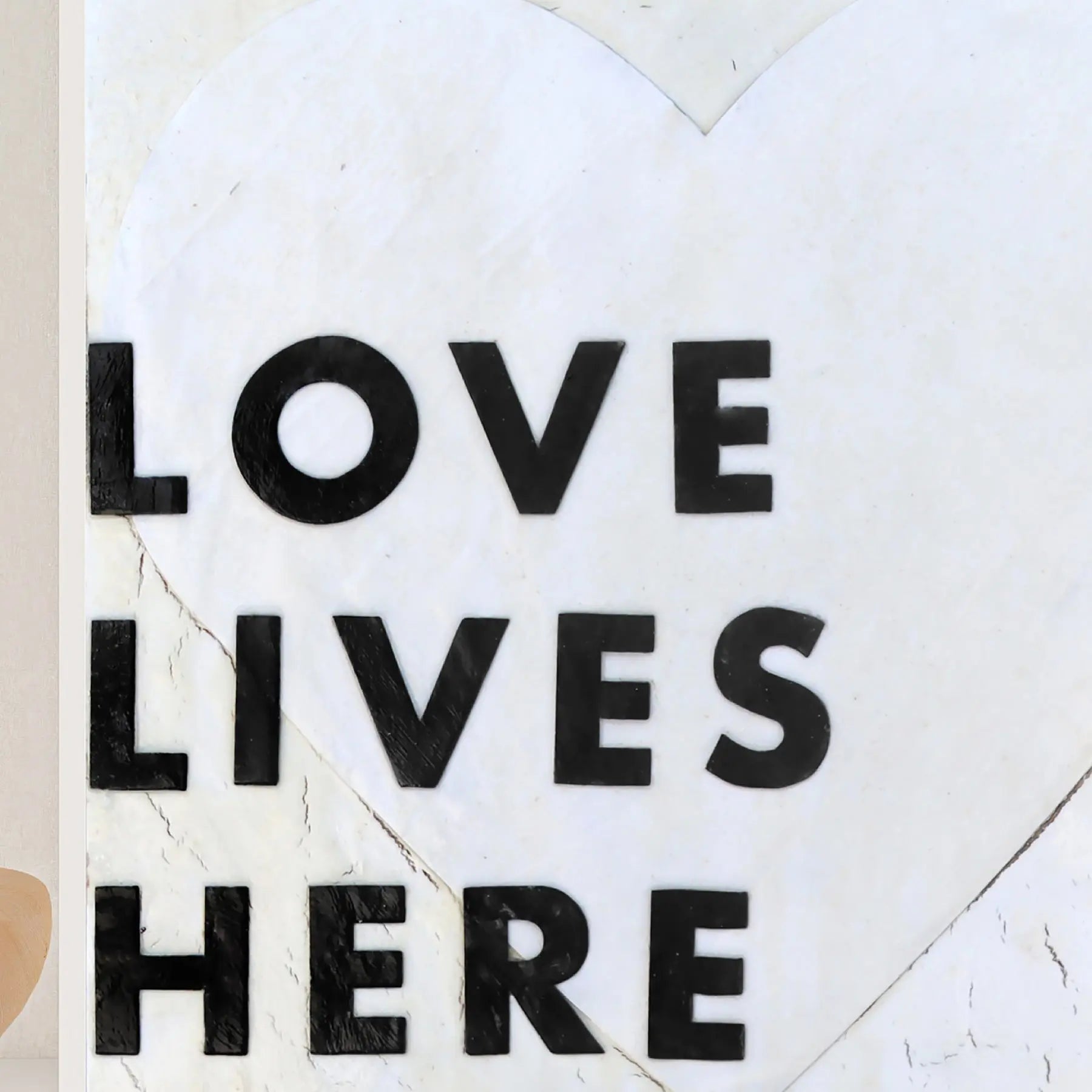 Black "LOVE LIVES HERE" text on a white heart background.