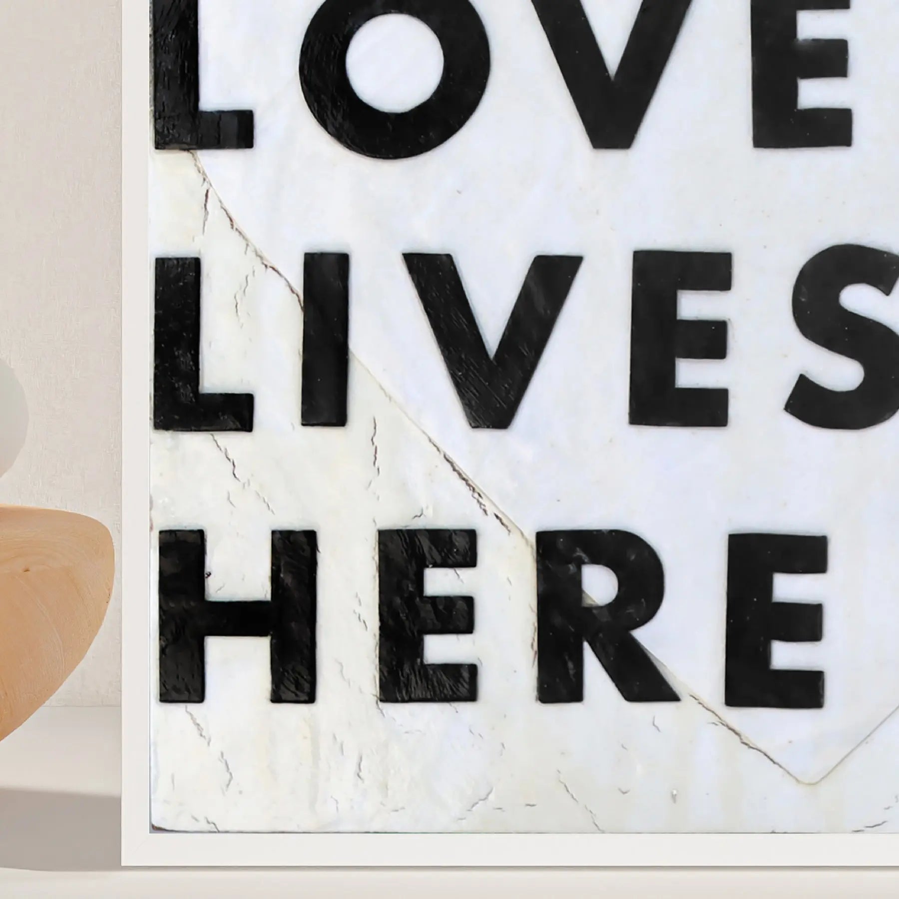 Love Lives Here art print with black textured letters on a cracked white background.