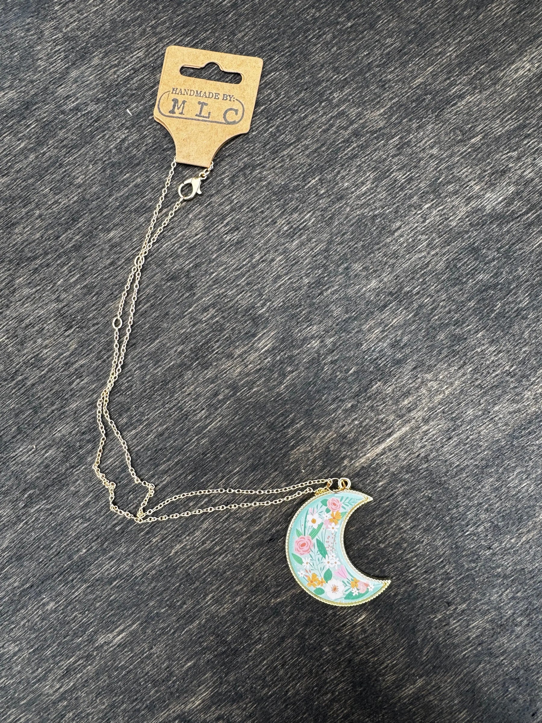 Floral moon necklace on a silver chain with tag reading \"Handmade by: MLC\"