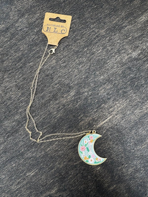 Floral moon necklace on a silver chain with tag reading \"Handmade by: MLC\"