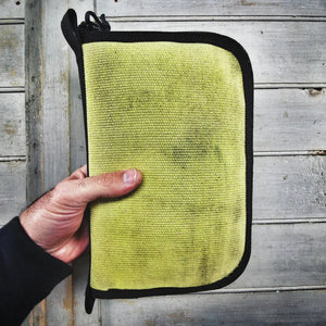 Large yellow canvas dopp bag with zipper closure being held by a hand.