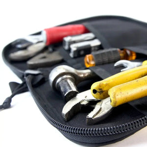 Open black zippered bag filled with assorted tools including pliers and a wrench.