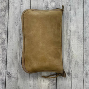 Brown suede toiletry bag with zipper closure and pull tab, laid flat.
