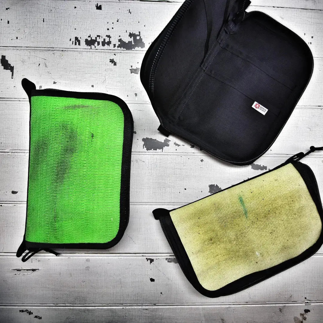 Green and black zippered dopp bag with a yellow zippered pouch on white wood.