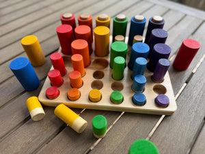 Wooden sorting tray with colorful pegs in red, orange, yellow, green, blue, and purple.