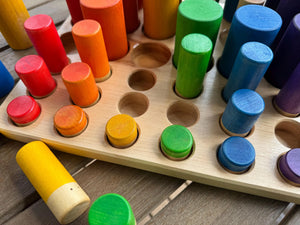 Wooden sorting tray with red, orange, yellow, green, blue, and purple pegs.