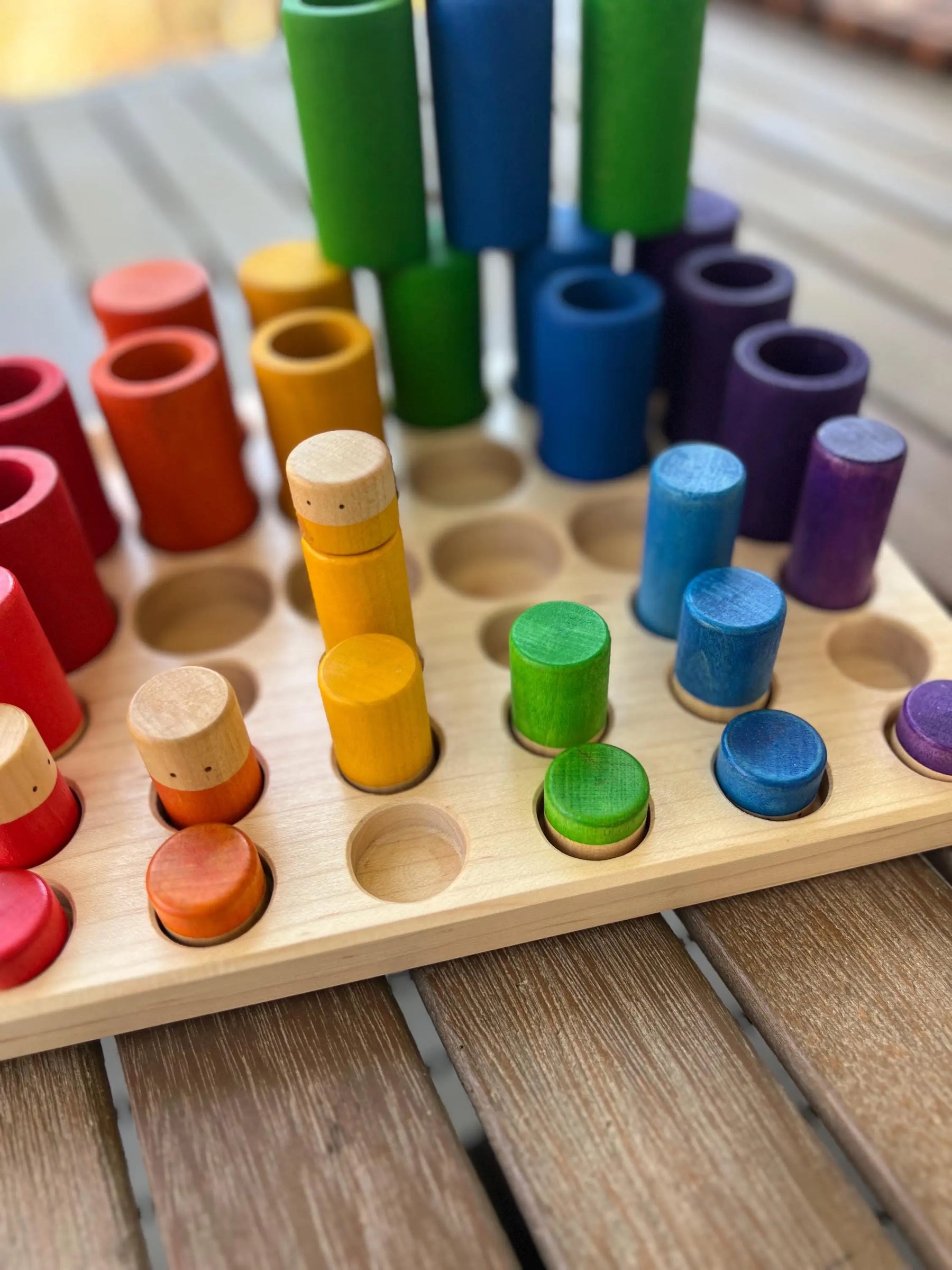 Wooden sorting tray with colorful pegs for color sorting and educational play.
