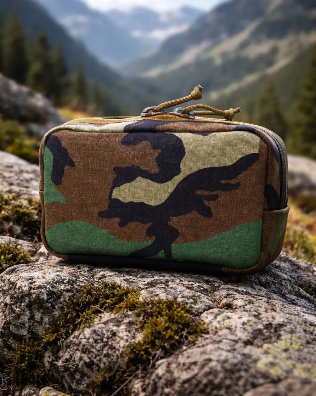 Woodland camouflage fanny pack on a rock with mountains in the background.